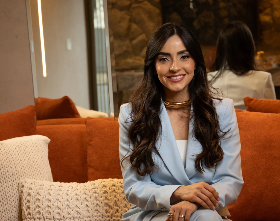 Andressa Rada sorrindo, sentada em um sofá